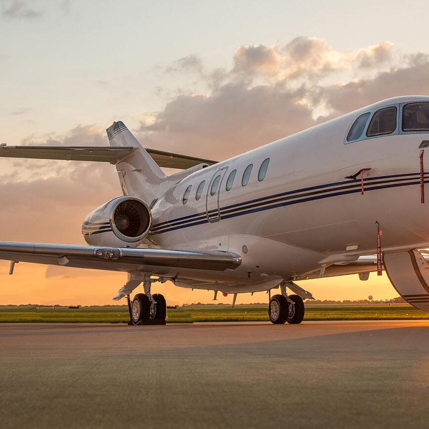 Corporate business jet setting on ramp with door open and sun setting in the background.